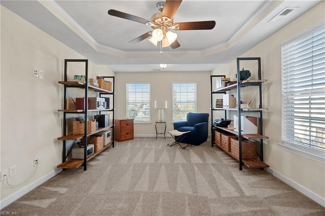 sitting room with a raised ceiling, light carpet, ceiling fan, and a healthy amount of sunlight