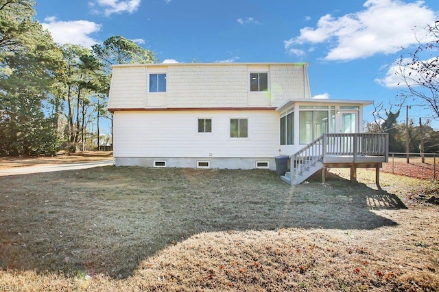 back of property featuring a sunroom, a deck, and a lawn