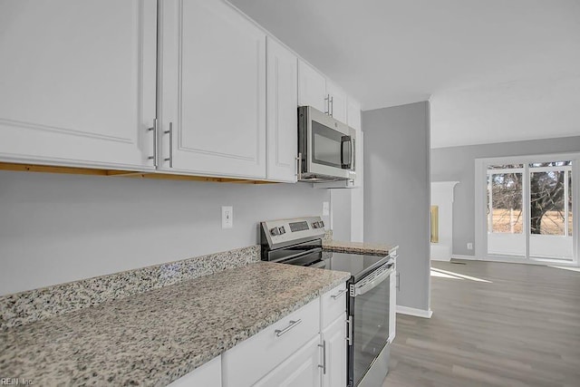 kitchen featuring white cabinets, appliances with stainless steel finishes, light hardwood / wood-style floors, and light stone countertops