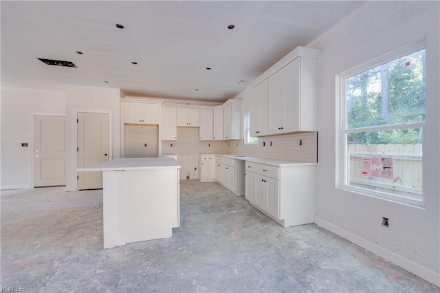 kitchen with a kitchen island, white cabinetry, and tasteful backsplash