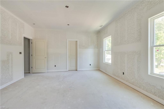 unfurnished room featuring a wealth of natural light and baseboards