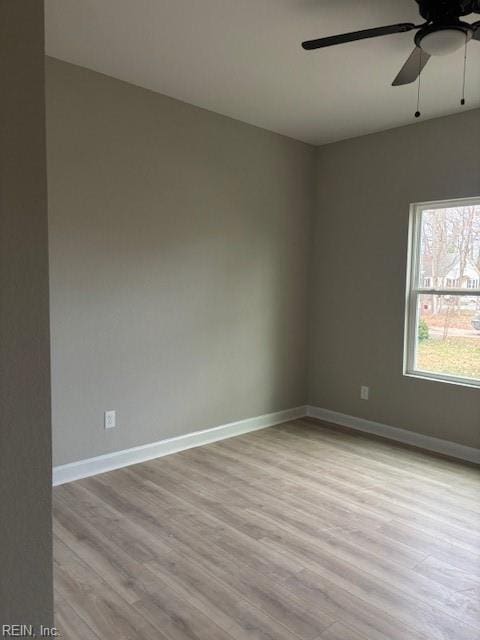 empty room featuring light wood finished floors, baseboards, and a ceiling fan