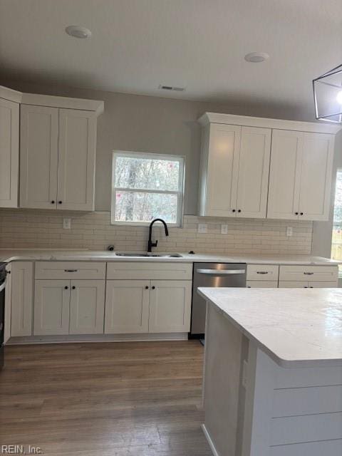 kitchen featuring light wood finished floors, light countertops, stainless steel dishwasher, and a sink