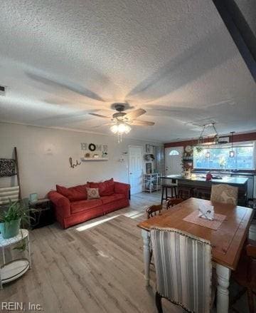 dining area with ceiling fan, light hardwood / wood-style floors, and a textured ceiling