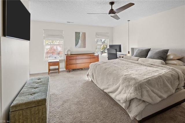 carpeted bedroom with ceiling fan and a textured ceiling