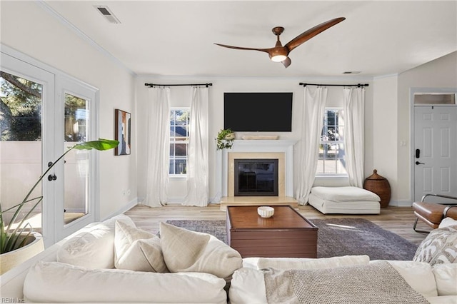 living room with ceiling fan, crown molding, and light hardwood / wood-style flooring