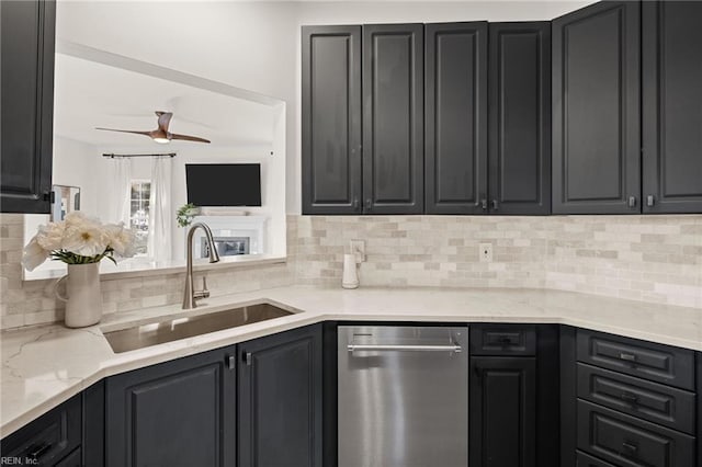 kitchen featuring ceiling fan, dishwasher, sink, light stone countertops, and tasteful backsplash