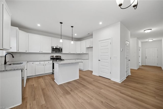 kitchen with light stone countertops, sink, a center island, white cabinets, and appliances with stainless steel finishes