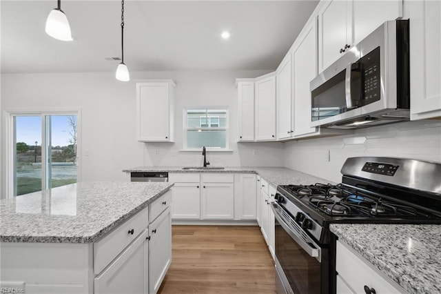 kitchen with white cabinets, decorative light fixtures, sink, and appliances with stainless steel finishes