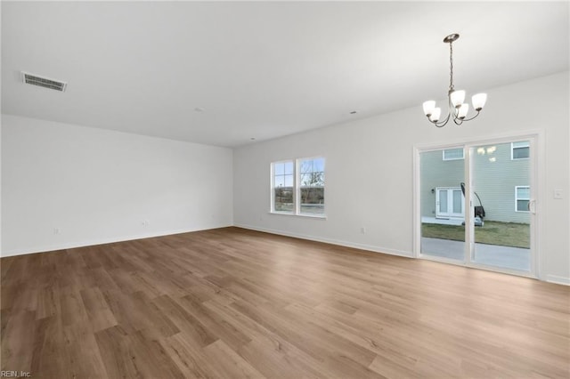 empty room featuring light wood-type flooring and an inviting chandelier