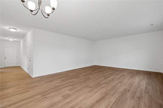 unfurnished room featuring light hardwood / wood-style flooring and a notable chandelier