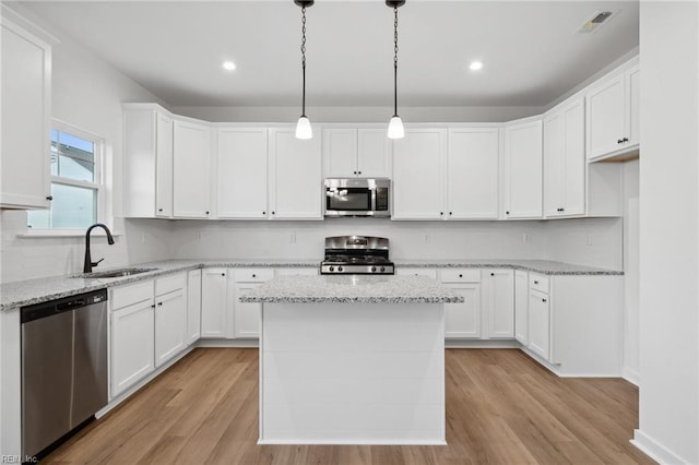 kitchen with a center island, sink, hanging light fixtures, stainless steel appliances, and white cabinets