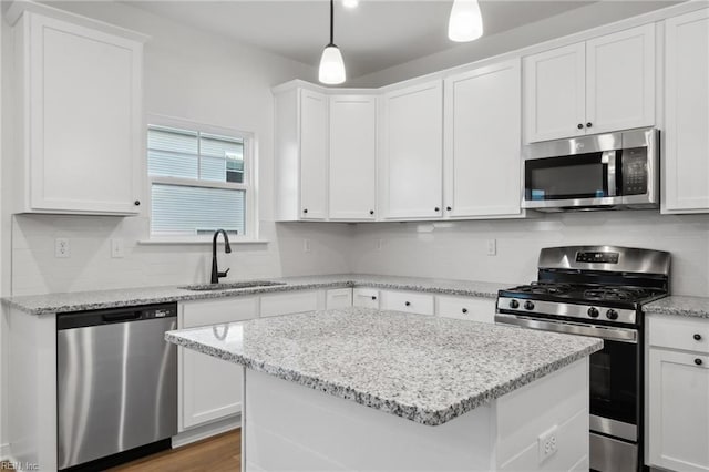 kitchen featuring sink, hanging light fixtures, stainless steel appliances, decorative backsplash, and white cabinets