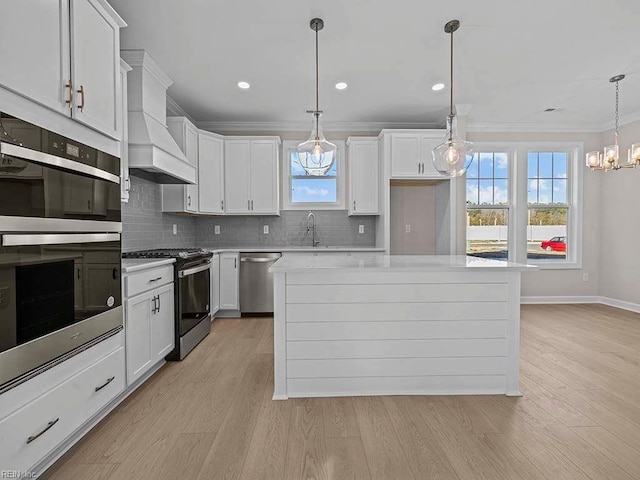 kitchen with a center island, premium range hood, white cabinets, appliances with stainless steel finishes, and decorative light fixtures