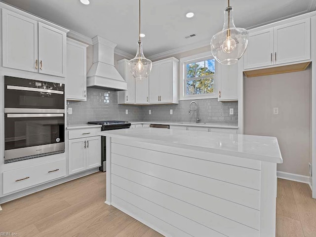 kitchen featuring white cabinets, pendant lighting, appliances with stainless steel finishes, and custom exhaust hood