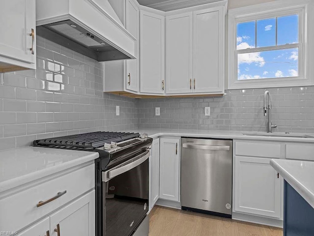 kitchen with custom range hood, stainless steel appliances, white cabinetry, and sink