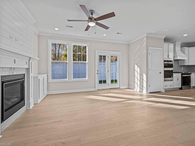 unfurnished living room with crown molding, a fireplace, ceiling fan, and light wood-type flooring