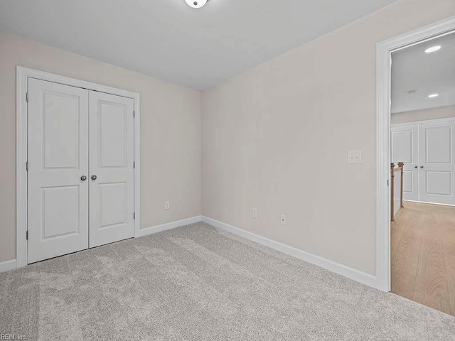 unfurnished bedroom featuring light colored carpet and a closet