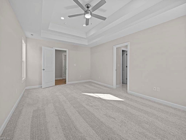 carpeted spare room featuring ceiling fan and a tray ceiling