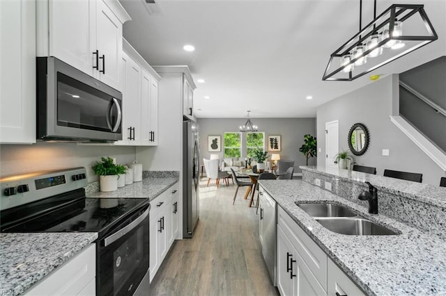 kitchen featuring stainless steel appliances, dark wood-type flooring, sink, white cabinets, and hanging light fixtures