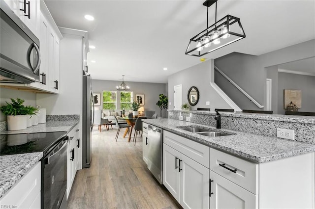 kitchen featuring sink, stainless steel appliances, light stone counters, light hardwood / wood-style floors, and white cabinets