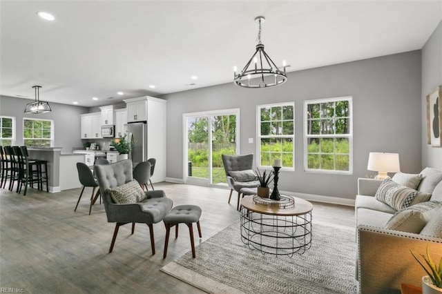 living room featuring light wood-type flooring, a wealth of natural light, and a notable chandelier