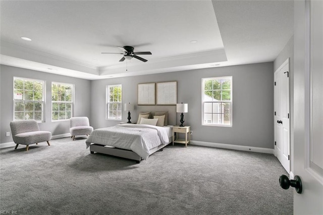 bedroom with carpet, ceiling fan, a tray ceiling, and multiple windows