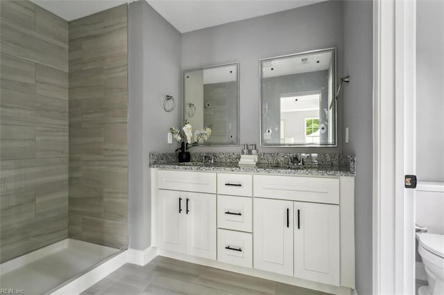 bathroom with a tile shower, vanity, and toilet