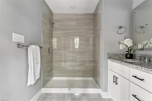 bathroom with a tile shower and vanity