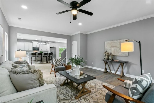 living room featuring ceiling fan, light wood-type flooring, and ornamental molding