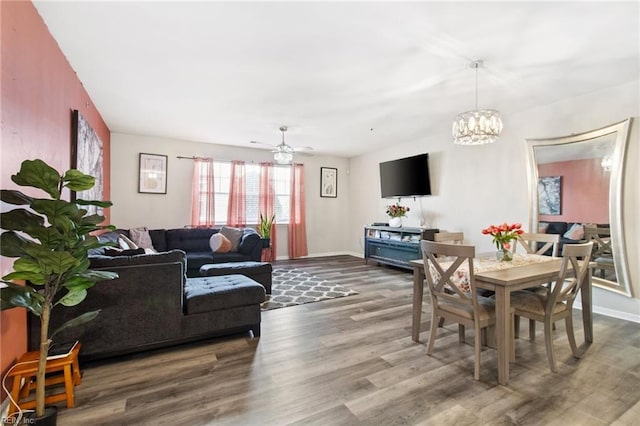 living room featuring wood-type flooring and ceiling fan with notable chandelier