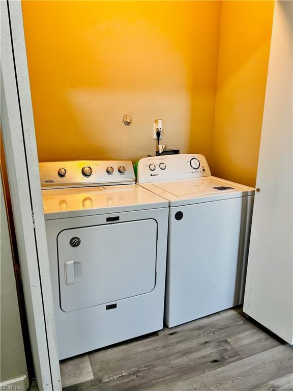 clothes washing area with light hardwood / wood-style flooring and washing machine and clothes dryer