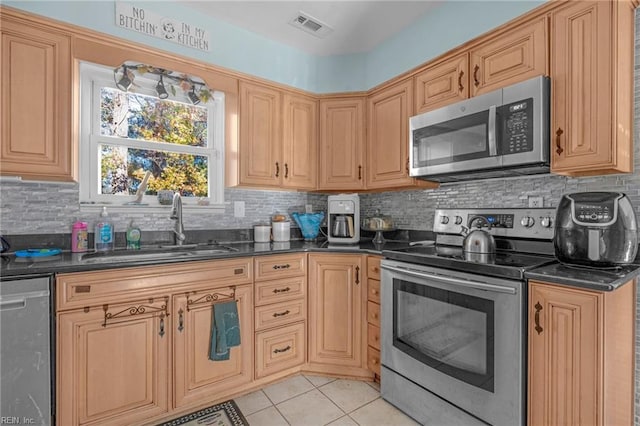 kitchen featuring backsplash, sink, light tile patterned floors, and stainless steel appliances