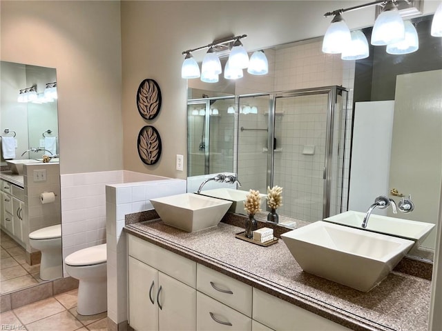 bathroom with vanity, a shower with door, tile patterned flooring, toilet, and tile walls