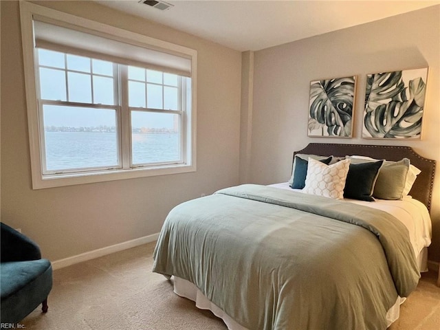 bedroom featuring a water view and light colored carpet