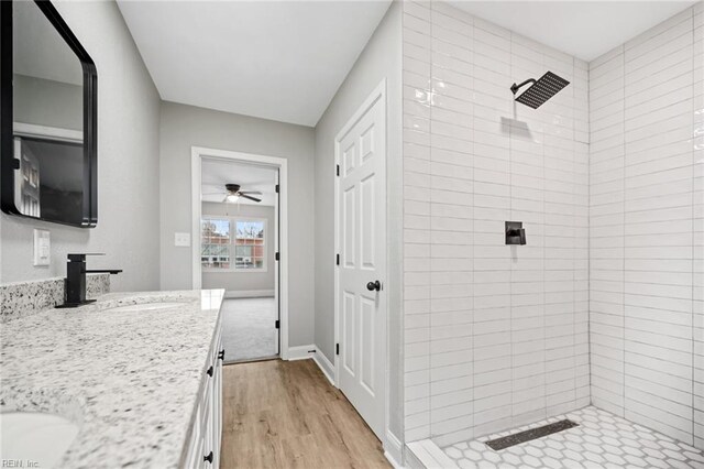 bathroom featuring hardwood / wood-style flooring, vanity, ceiling fan, and a tile shower