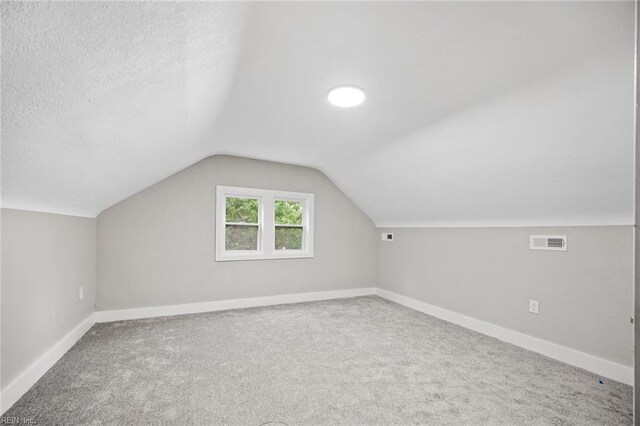 bonus room featuring carpet flooring, a textured ceiling, and vaulted ceiling