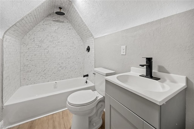 full bathroom with hardwood / wood-style floors, vanity, tiled shower / bath combo, toilet, and a textured ceiling