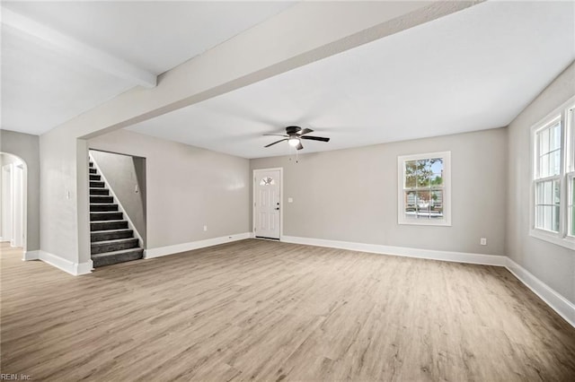 unfurnished living room featuring beamed ceiling, wood-type flooring, and ceiling fan