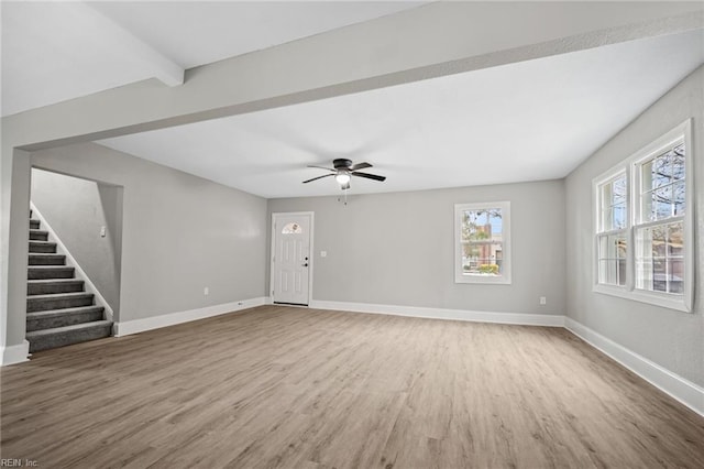 unfurnished living room featuring beamed ceiling, ceiling fan, and wood-type flooring