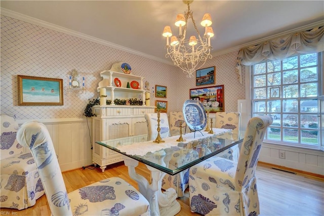 dining room with light hardwood / wood-style floors, ornamental molding, and an inviting chandelier