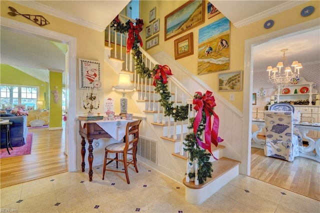 staircase with hardwood / wood-style flooring, an inviting chandelier, and crown molding