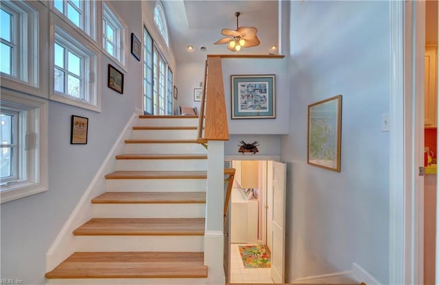 stairs with ceiling fan and a towering ceiling