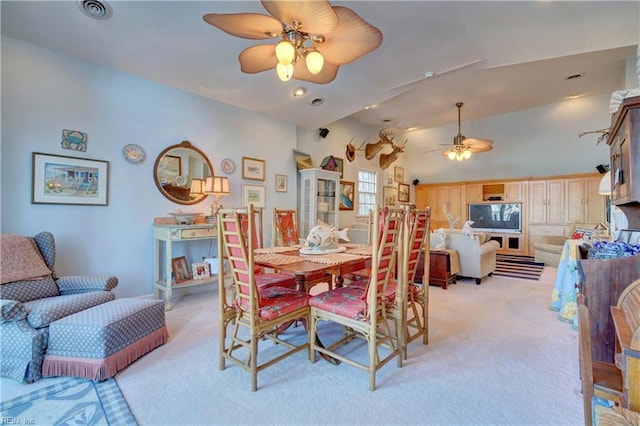 carpeted dining room with ceiling fan and vaulted ceiling