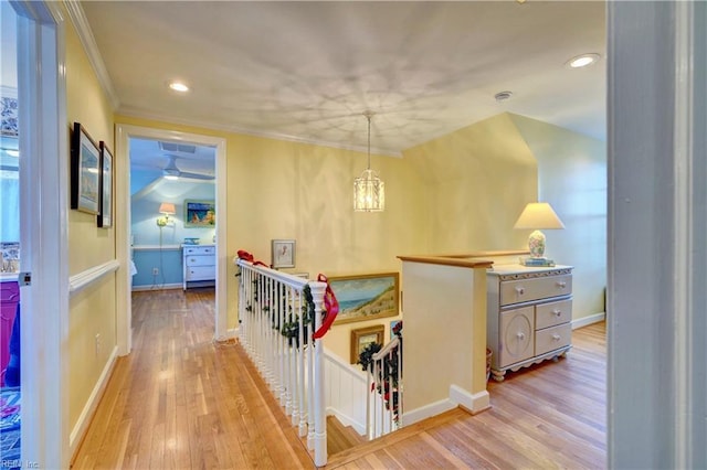 hallway featuring crown molding, light hardwood / wood-style flooring, and a chandelier