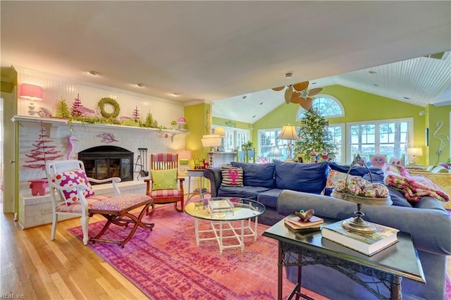 living room featuring a brick fireplace, a healthy amount of sunlight, lofted ceiling, and light hardwood / wood-style flooring