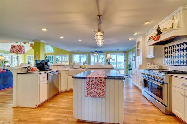 kitchen featuring decorative light fixtures, a kitchen island, light wood-type flooring, and stainless steel appliances