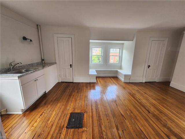 interior space with white cabinets, light stone counters, sink, and light hardwood / wood-style flooring