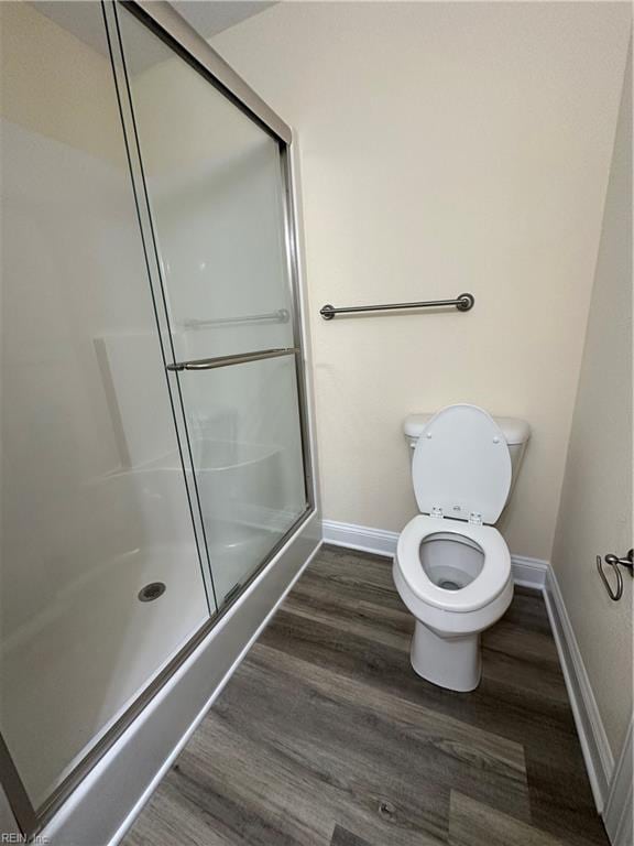 bathroom with hardwood / wood-style flooring, toilet, and a shower with door