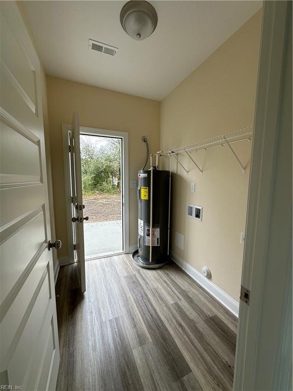 laundry area with water heater, dark wood-type flooring, and washer hookup